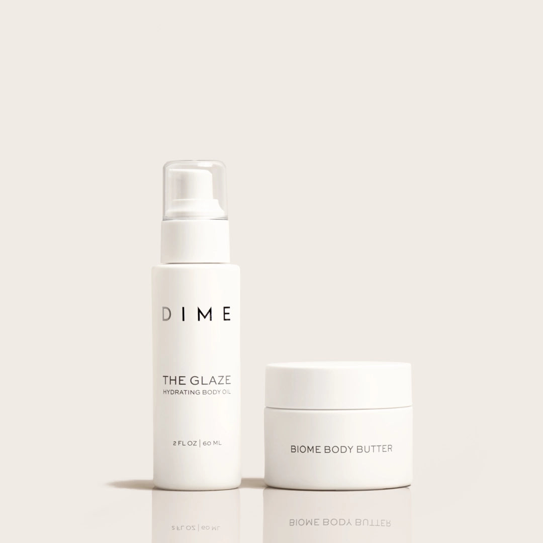 Two white skincare products: a spray bottle labeled "The Glaze Hydrating Body Oil" and a jar labeled "Biome Body Butter."