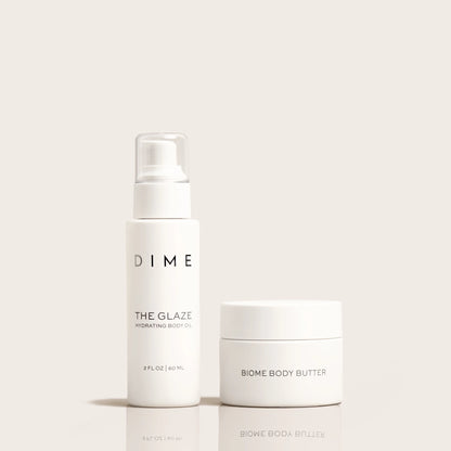 Two white skincare products: a spray bottle labeled "The Glaze Hydrating Body Oil" and a jar labeled "Biome Body Butter."