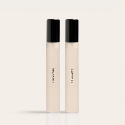 Two cream-colored fragrance rollers with black caps labeled "7 SUMMERS" on a neutral background.