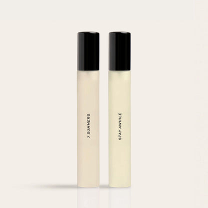 Two pale liquid fragrances in black-capped bottles labeled "7 Summers" and "Stay Awhile."