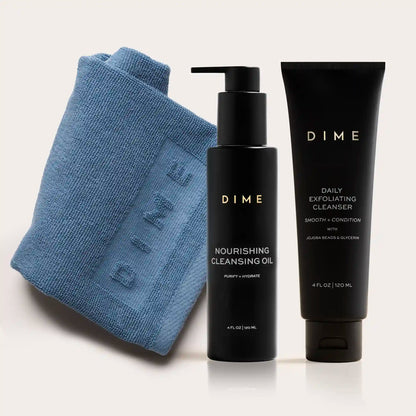 Blue textured cleansing cloth with black pump bottle of nourishing cleansing oil and black tube of daily exfoliating cleanser