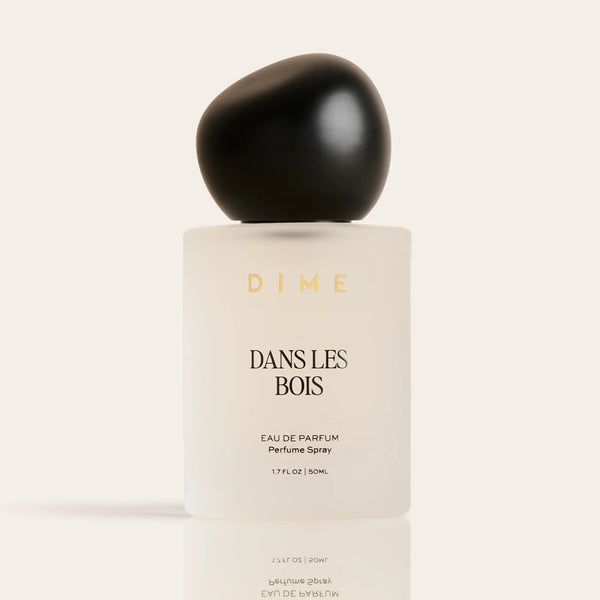 Cream-colored perfume bottle labeled "Dans Les Bois" with black spherical cap, 1.7 FL OZ, eau de parfum spray.