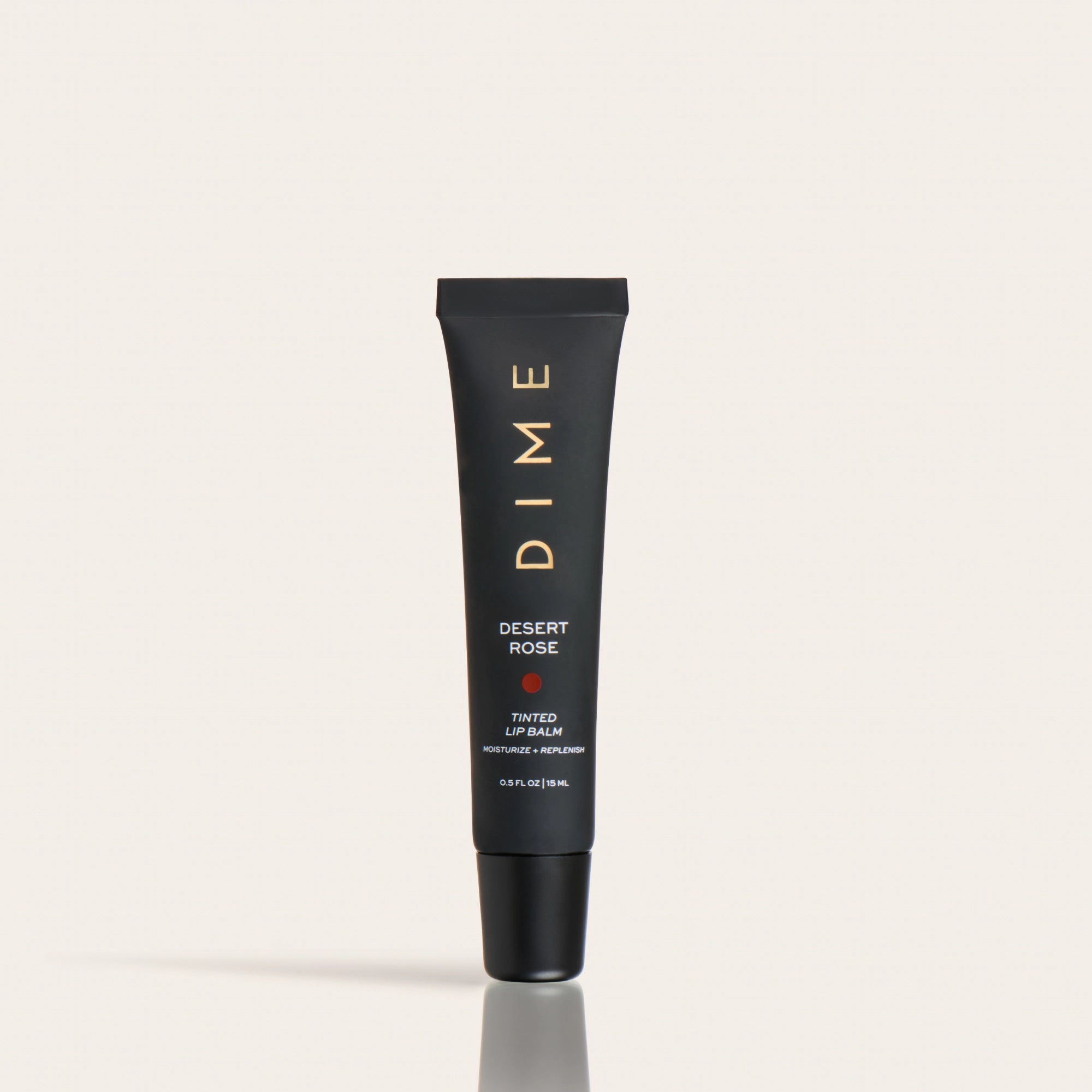 Black tube of Desert Rose tinted lip balm with gold text and cap against a neutral background.