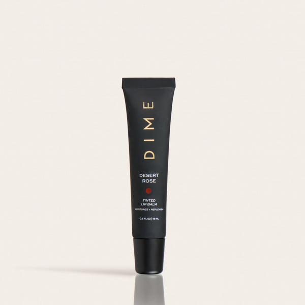 Black tube of Desert Rose tinted lip balm with gold text and cap against a neutral background.