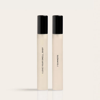 Two cylindrical fragrance bottles with black caps and cream-colored bodies labeled "I Love Your Smell Baby" and "7 Summers."
