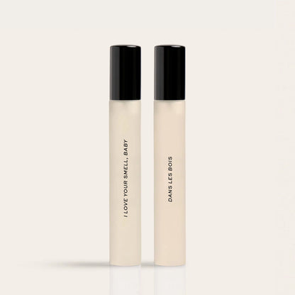 Two cream-colored rollerballs with black caps labeled "I Love Your Smell Baby" and "Dawn's Les Bois".