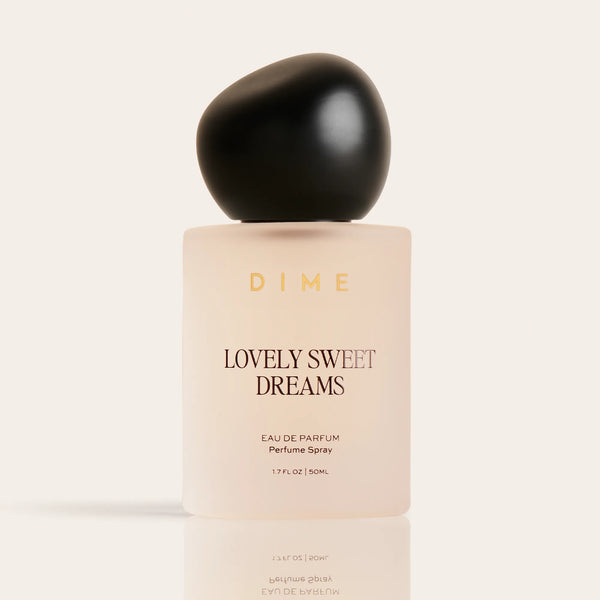 Cream-colored perfume bottle labeled "Lovely Sweet Dreams" with black spherical cap, 1.7 fl oz size.