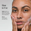 Person with medium skin tone applying lathered cleanser to face with both hands.