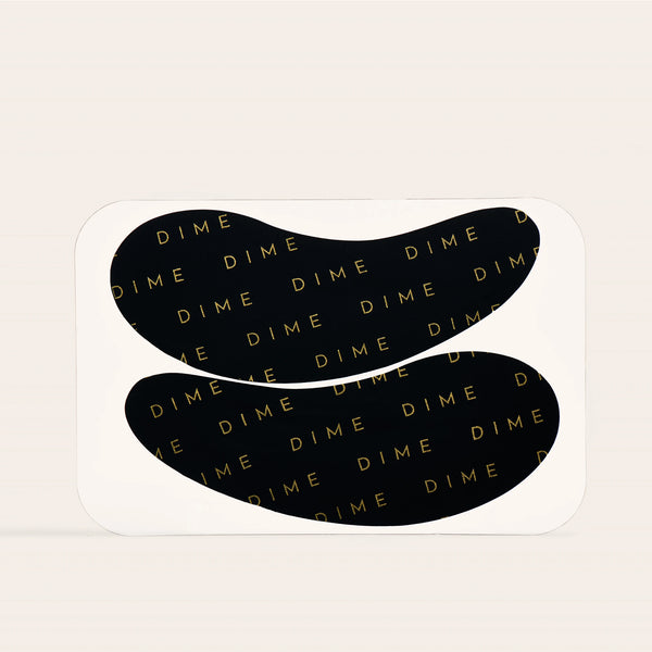 Pair of black curved silicone eye patches with gold "DIME" text pattern throughout.