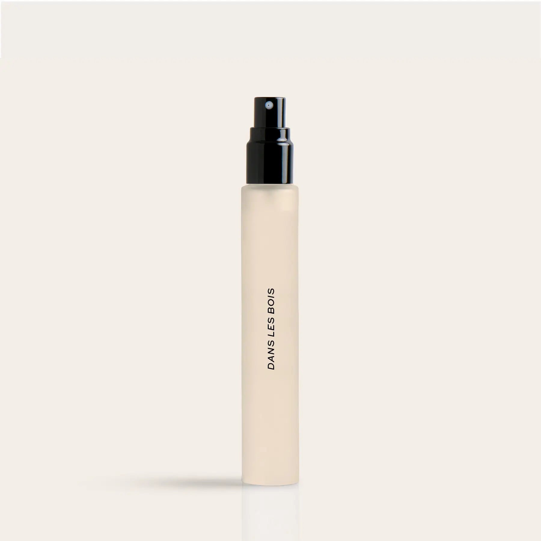 Cylindrical cream-colored spray bottle with black pump top and "DANS LES BOIS" text on side.