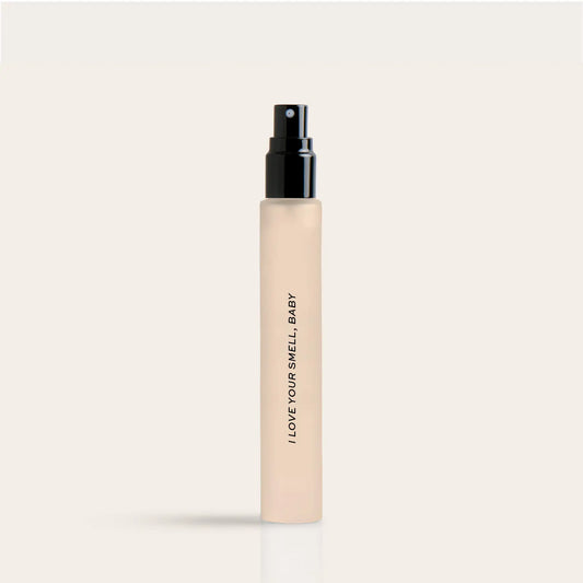 Cream-colored travel spray bottle with black pump top and "I LOVE YOUR SMELL BABY" text printed vertically on the bottle.