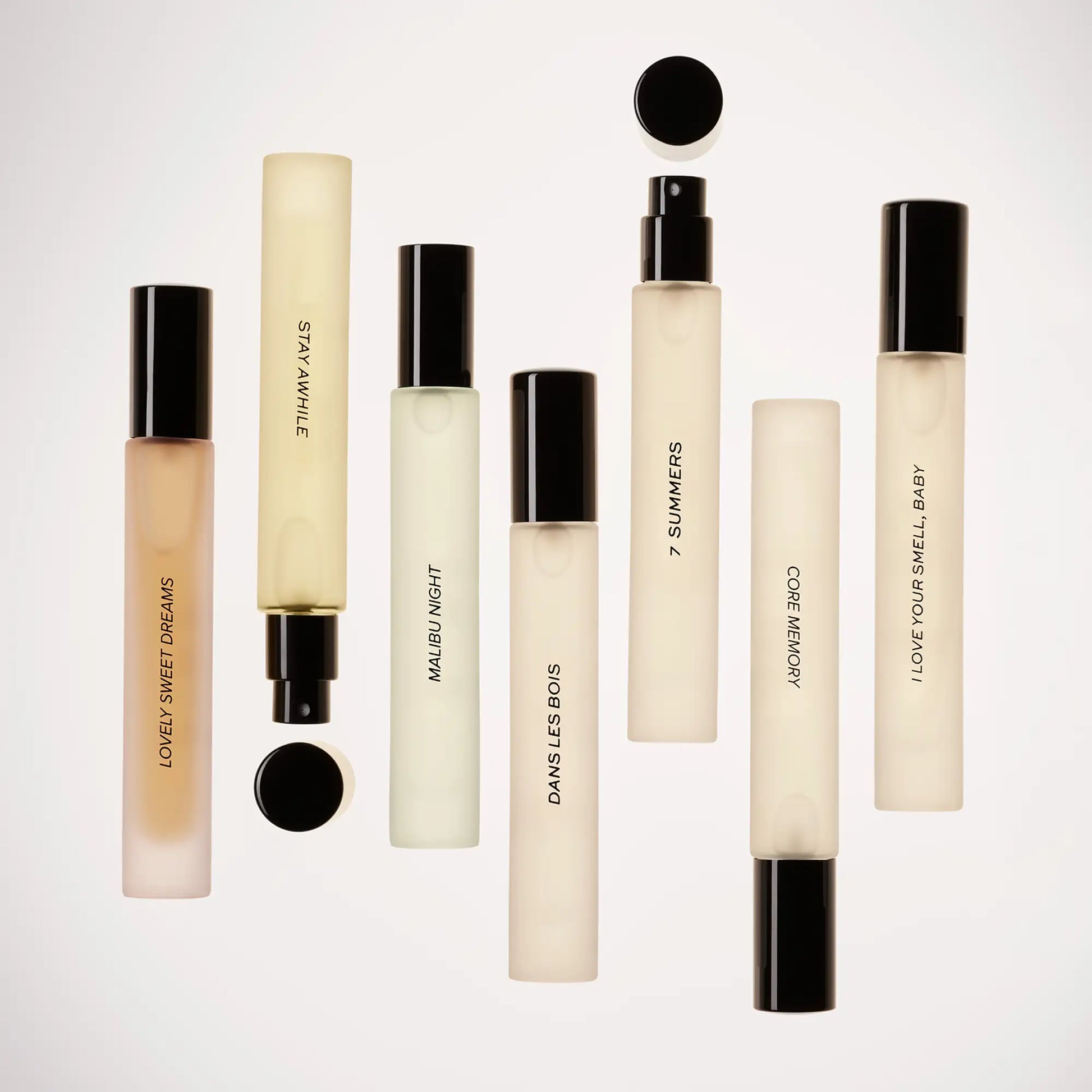 Perfume travel spray with cream-colored rectangular bottle, black cap, and spray nozzle containing pale liquid.